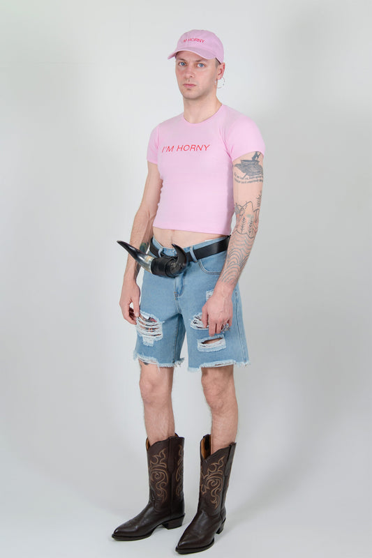 HORN BELT, full-length on a model with the I'M HORNY tee and cap, ripped denim shorts and brown cowboy boots