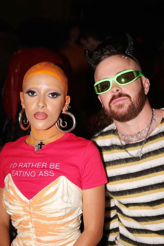 I'D RATHER BE EATING ASS T-SHIRT worn by Doja Cat at an event, under a ruched cream-and-orange dress