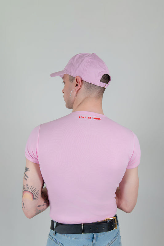 I'M HORNY T-SHIRT, back view on a model: plain light pink back with small red “EDNA ST LOUIS” text below the neckline