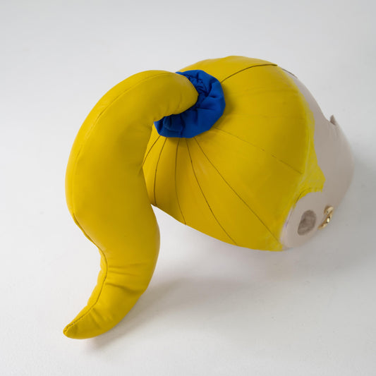 BOX HELMET on its own, from behind: curved yellow leather ponytail tied with a blue nylon scrunchie