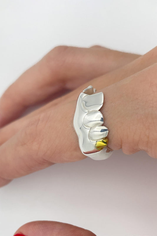 BOXER RING, side view on a finger: three sculpted silver teeth, the last one gold-plated