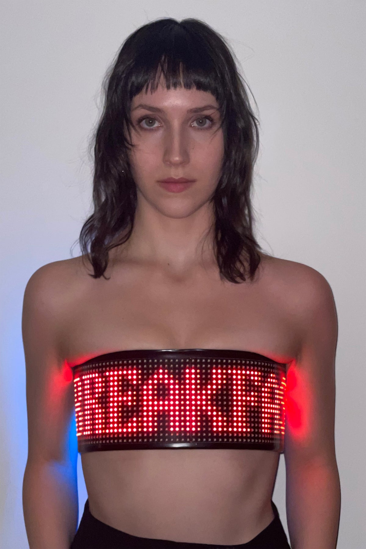 FOOD CART BANDEAU TOP worn strapless with black trousers, red LED lettering of “BREAKFAST” lit across the front