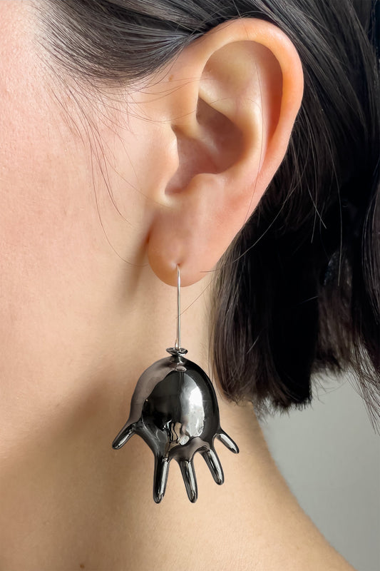 GLOVE BALLOON SINGLE EARRING on a model's ear: black hollow inflated-glove pendant on a long silver hook