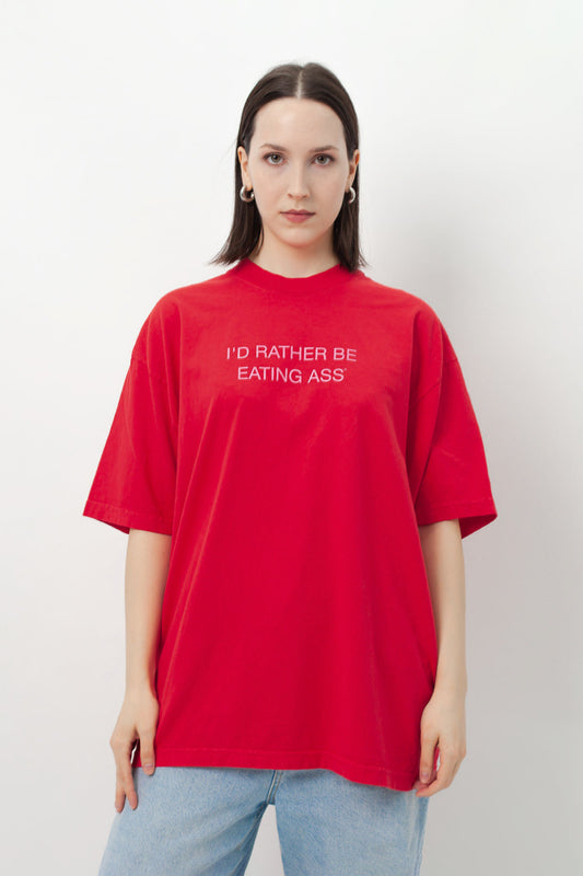 I'D RATHER BE EATING ASS OVERSIZED T-SHIRT on a model: red tee with pink "I'D RATHER BE EATING ASS" print, with jeans