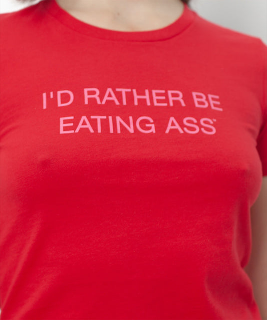 I'D RATHER BE EATING ASS T-SHIRT, close-up of the baby pink slogan printed across the red chest