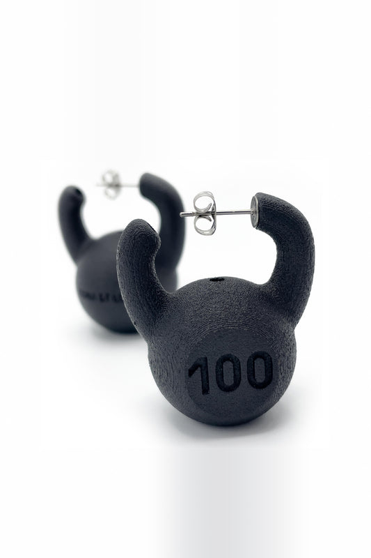 KETTLEBELL EARRINGS, angled view of the pair, the front one in focus showing the "100" and its silver post
