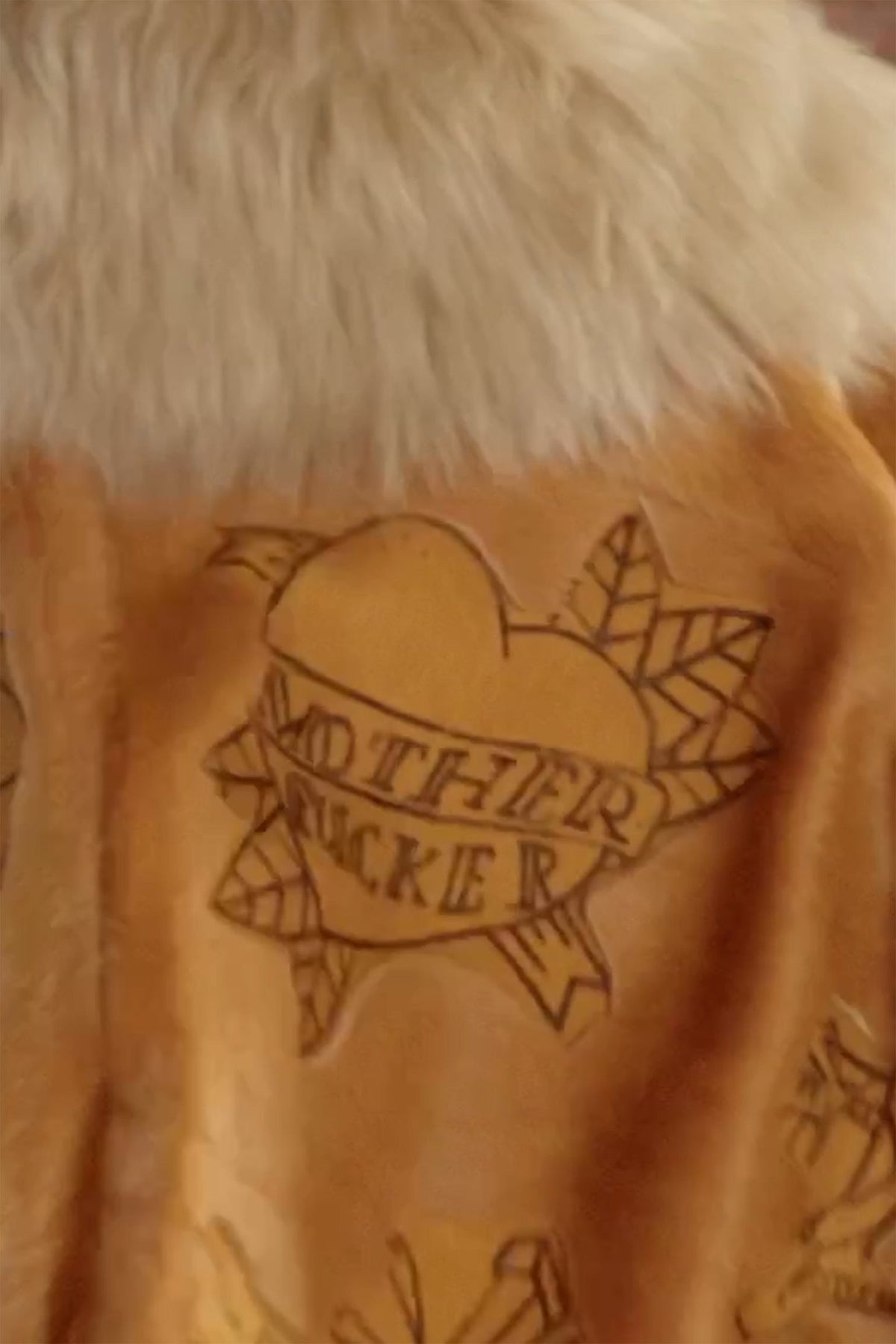 LOOK 3, Save A Horse, Ride A Cowboy: close-up, burnt heart and banner reading “MOTHER FUCKER” below the collar
