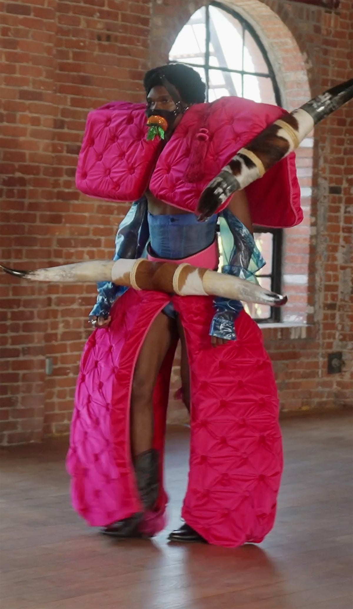 LOOK 5, Save A Horse, Ride A Cowboy: three-quarter view in motion by an arched window, pink velvet and bull horns