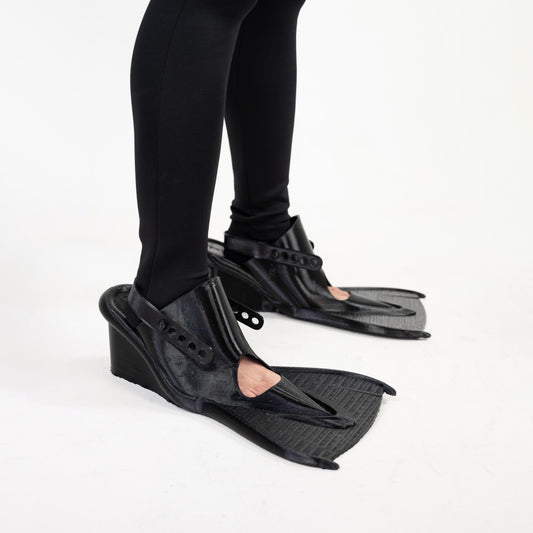 SCUBA HEELS worn with black leggings, square crop: black fin-shaped soles extending past the toes on wedge heels