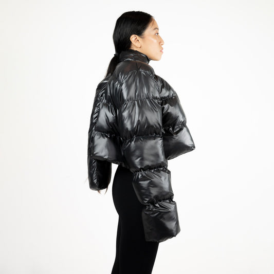 SCUBA PUFFER JACKET, side profile on a model: shiny black quilting, padded back panel and long oversized sleeves