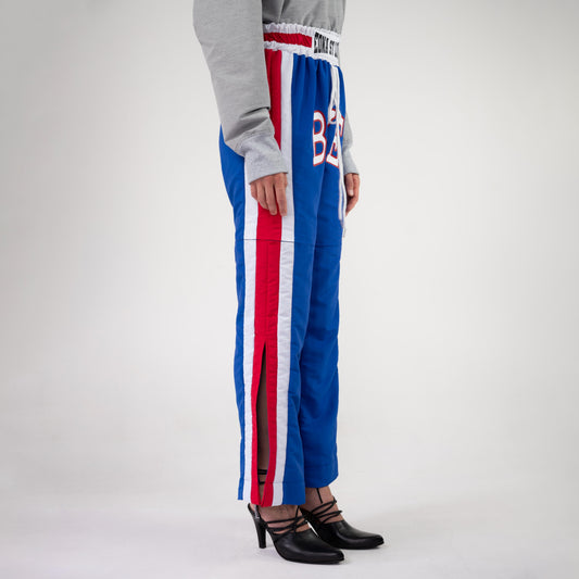 BOX TRACK PANT, side view on a model: red and white side stripe with an open side slit at the hem, slight flare