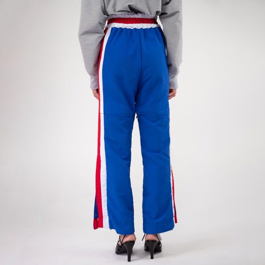 BOX TRACK PANT, back view on a model: plain blue back, red and white side stripes, slightly flared legs